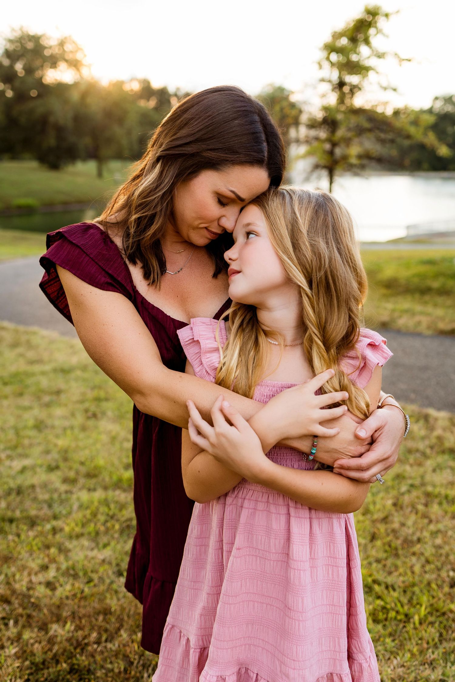 A tender moment between parent and child embracing outdoors at sunset in a grassy field.