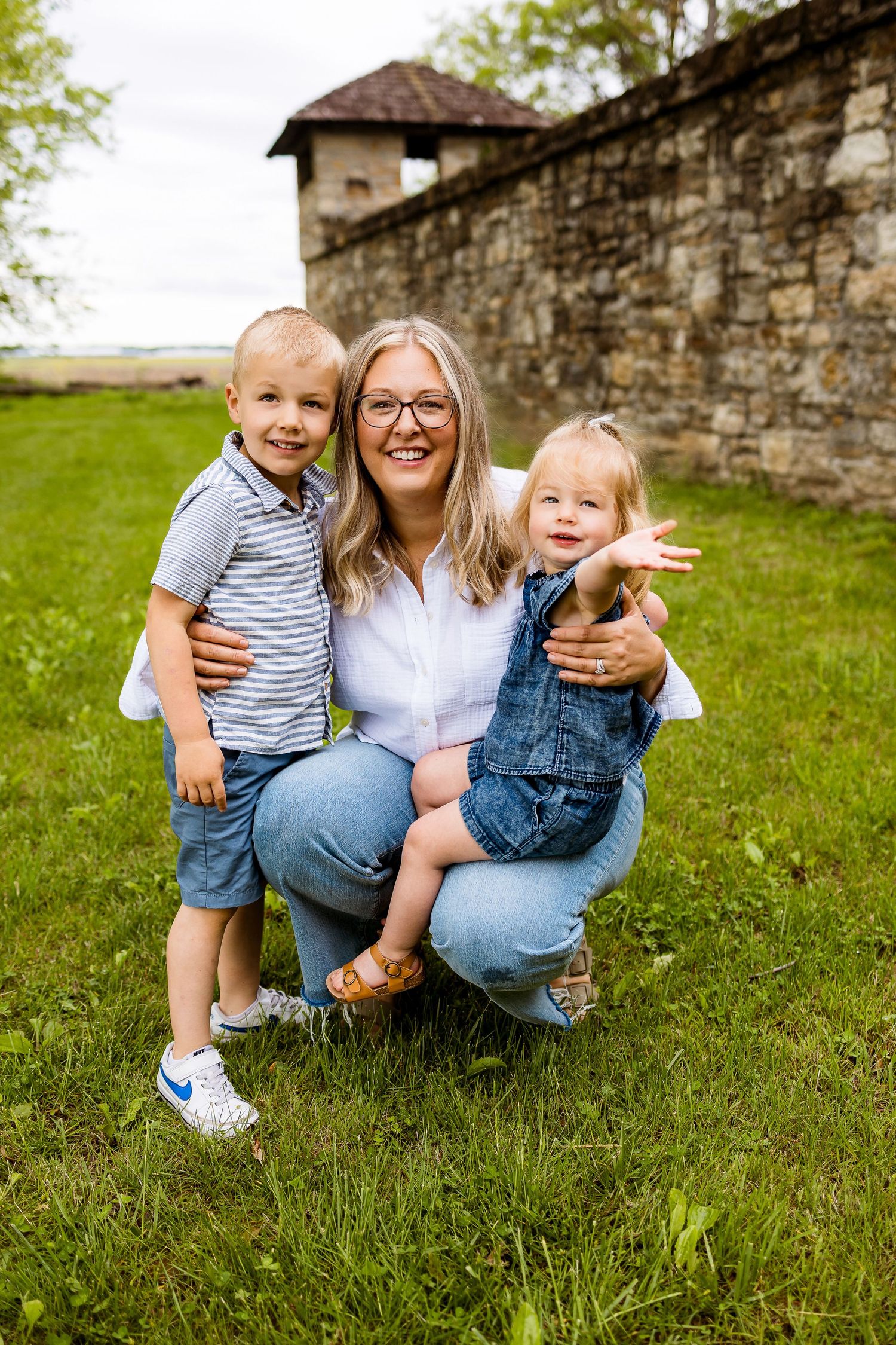 A happy family moment outdoors against a stone wall background on a sunny day.