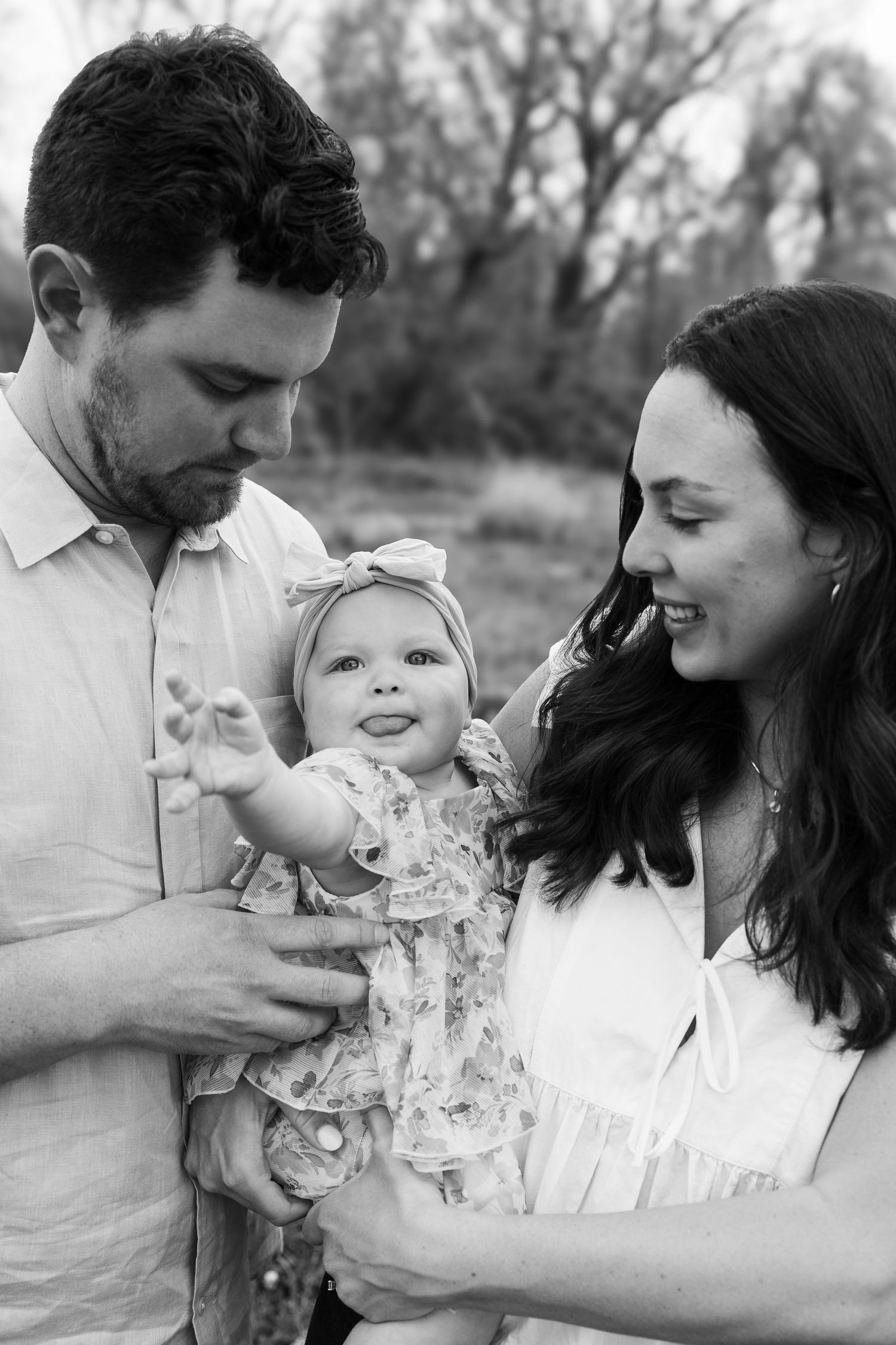 Black and white portrait of young family sharing joyful moment together outdoors.
