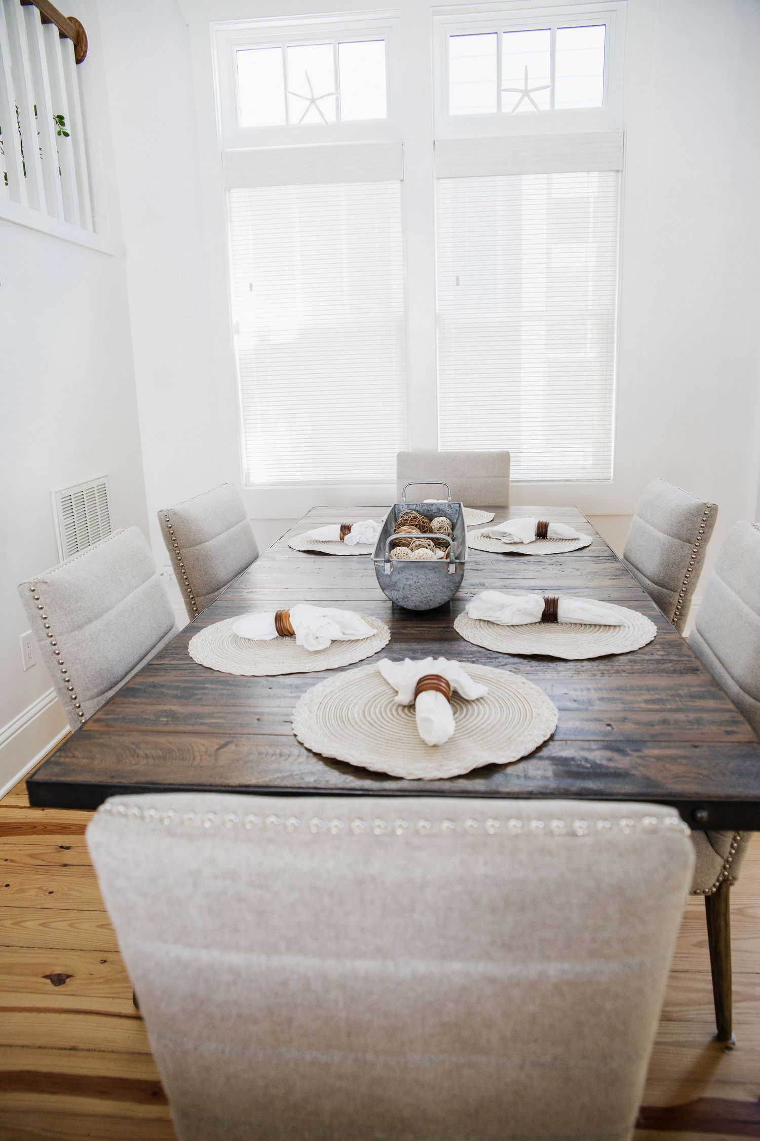 Minimalist dining nook with beige upholstered seating and rustic wooden table set for a meal.