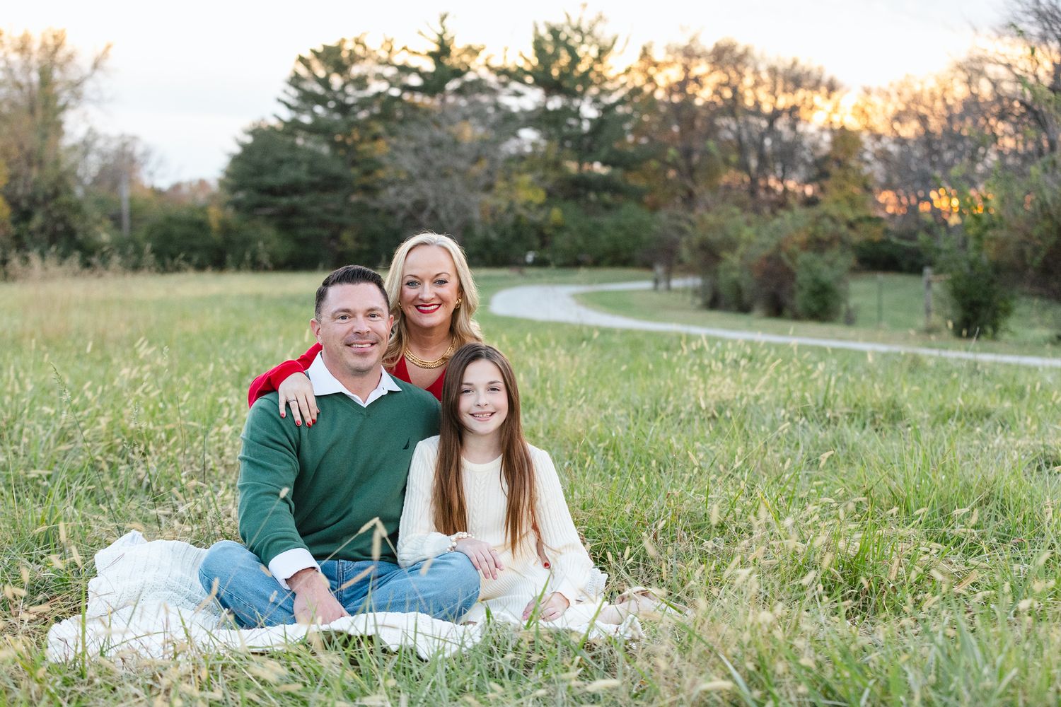 A family portrait session on a grassy field during golden hour.