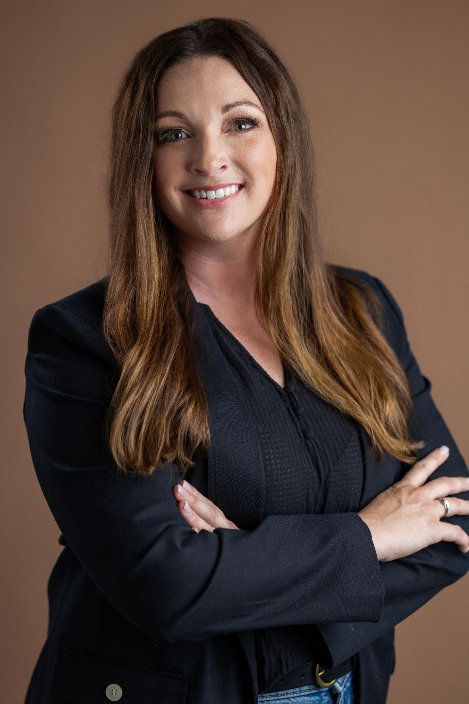 A person in a black blazer strikes various poses against a brown studio backdrop with warm lighting.
