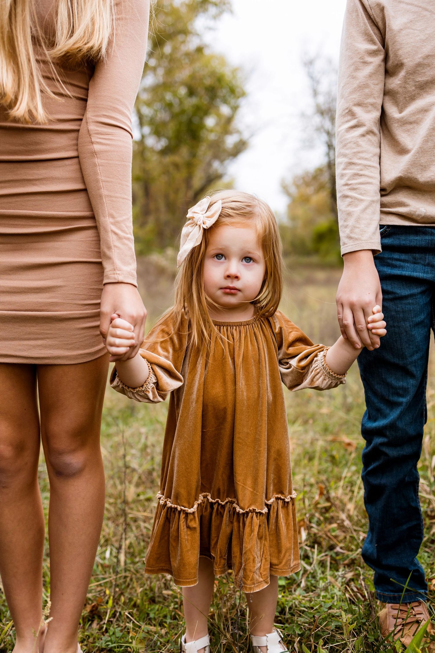 A series of cropped photos showing hands holding together and brown skirts in an outdoor grassy setting.