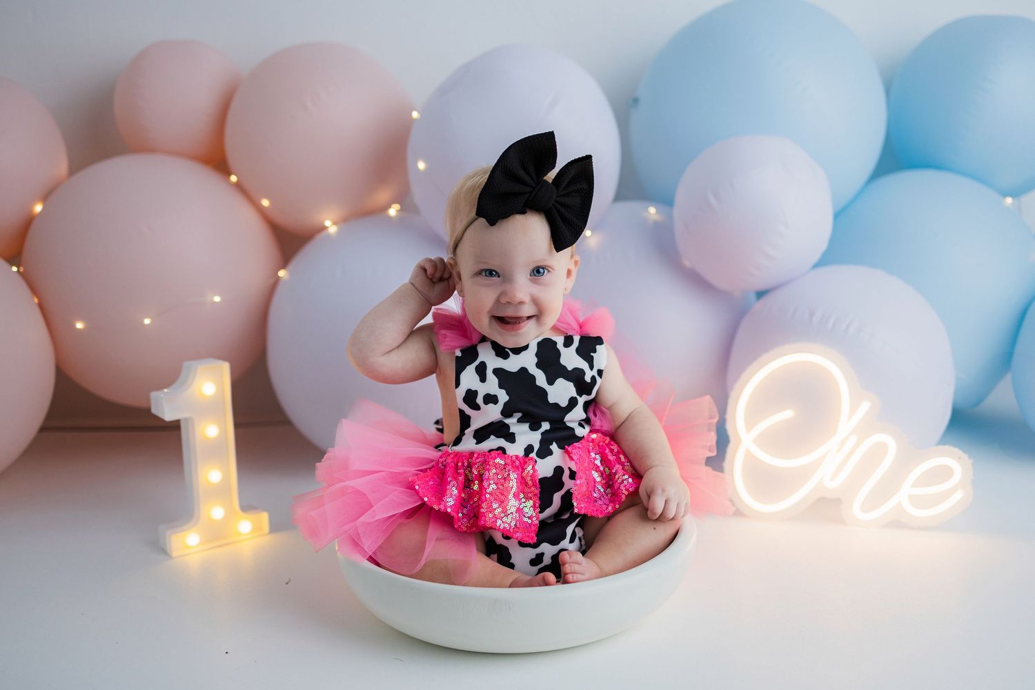 Romantic pastel blue and pink balloon arch with sparkling fairy lights creates a dreamy party atmosphere.