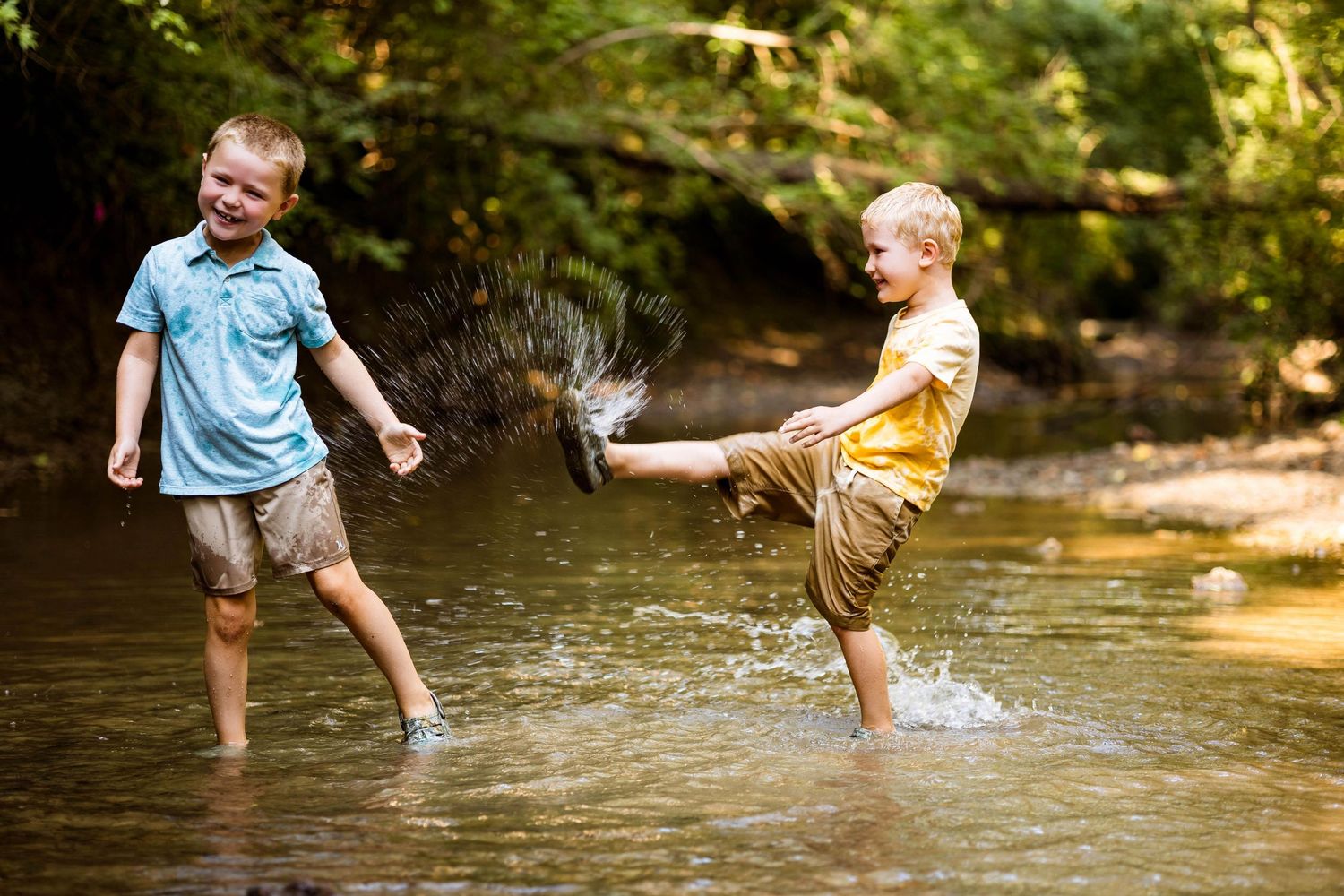 Kids splash and play in a shallow creek on a sunny summer day creating water ripples and fun memories.