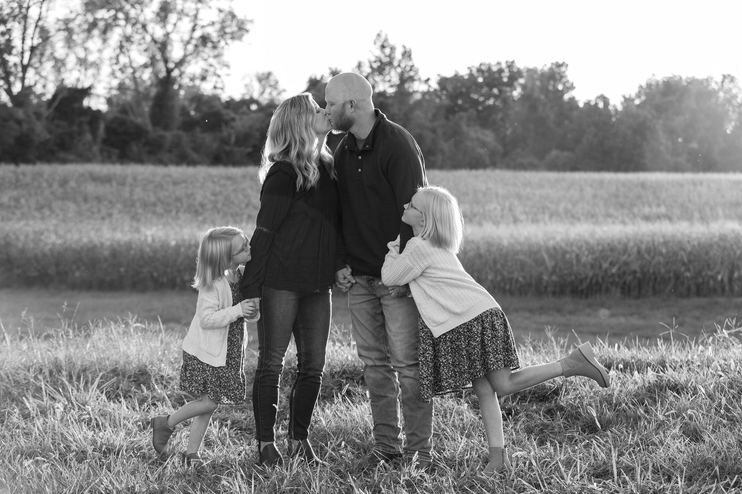 Family gathering in field during sunset for black and white portrait.
