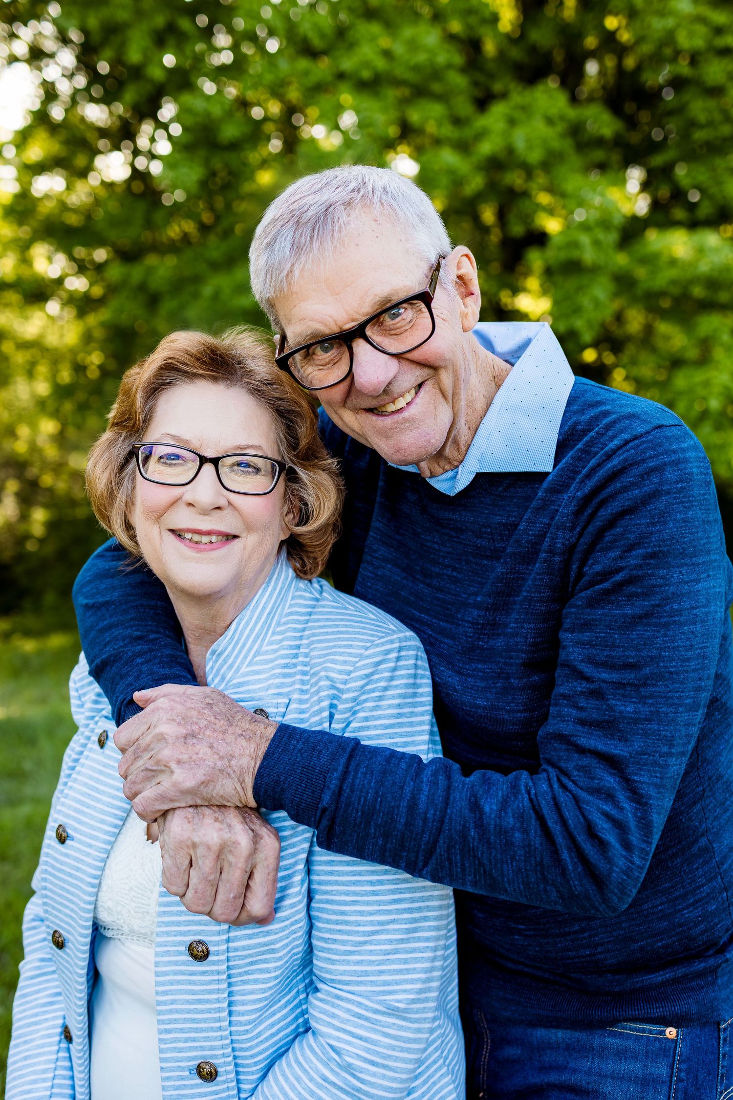 Senior couple embracing and smiling together outdoors wearing coordinating blue outfits.