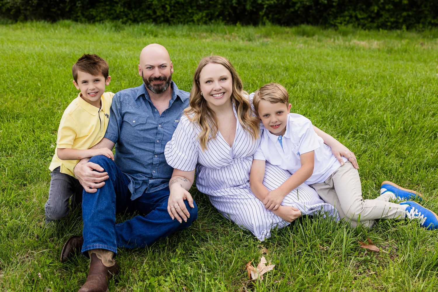 Family relaxing together on lush green grass during summer day.