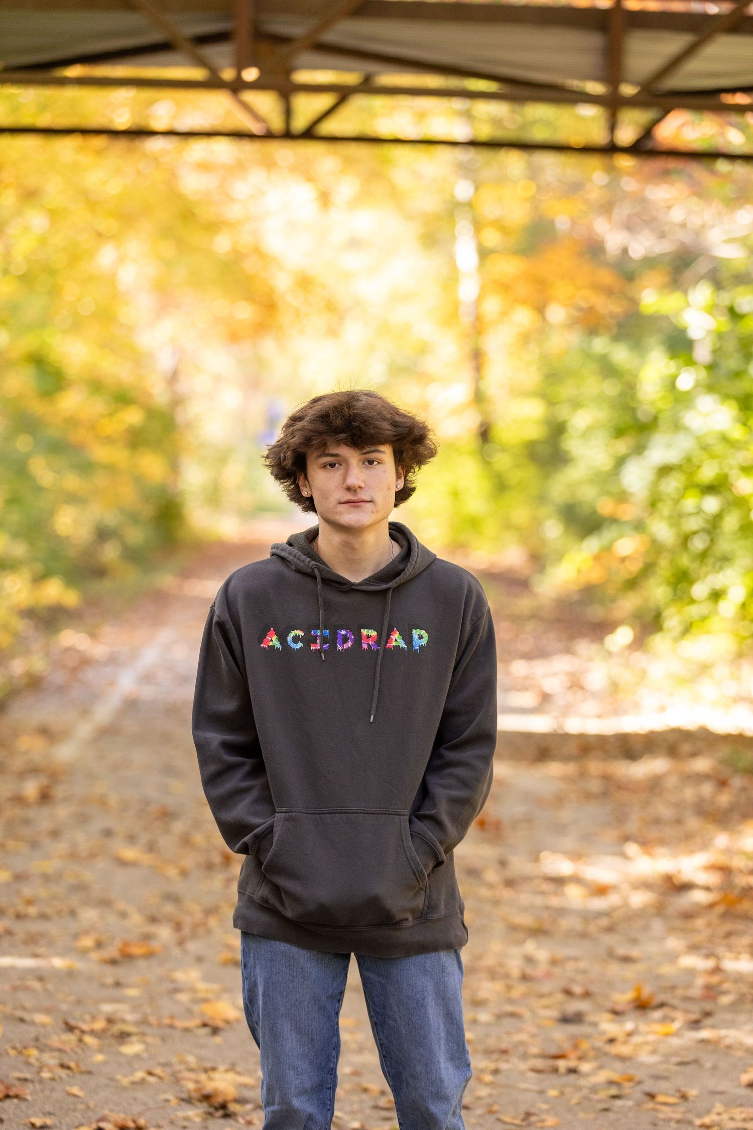 Fall outdoor portrait with person wearing dark Astrolab hoodie against autumn foliage.