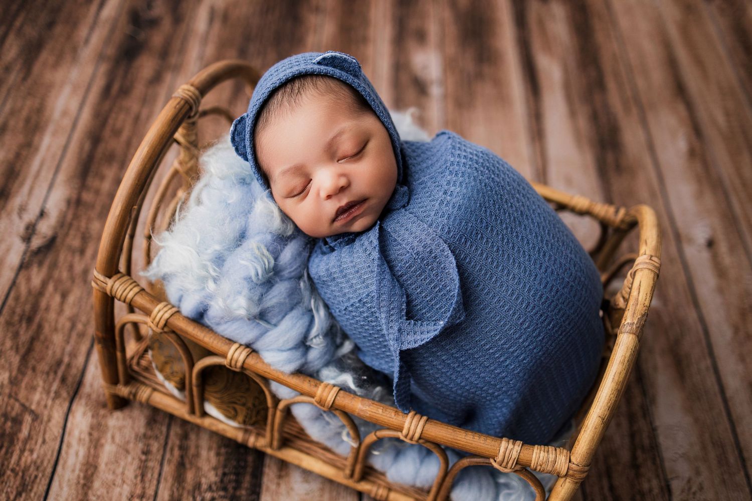 Collage of newborn baby photography showing peaceful sleeping poses in blue knit outfit against wooden backdrop.