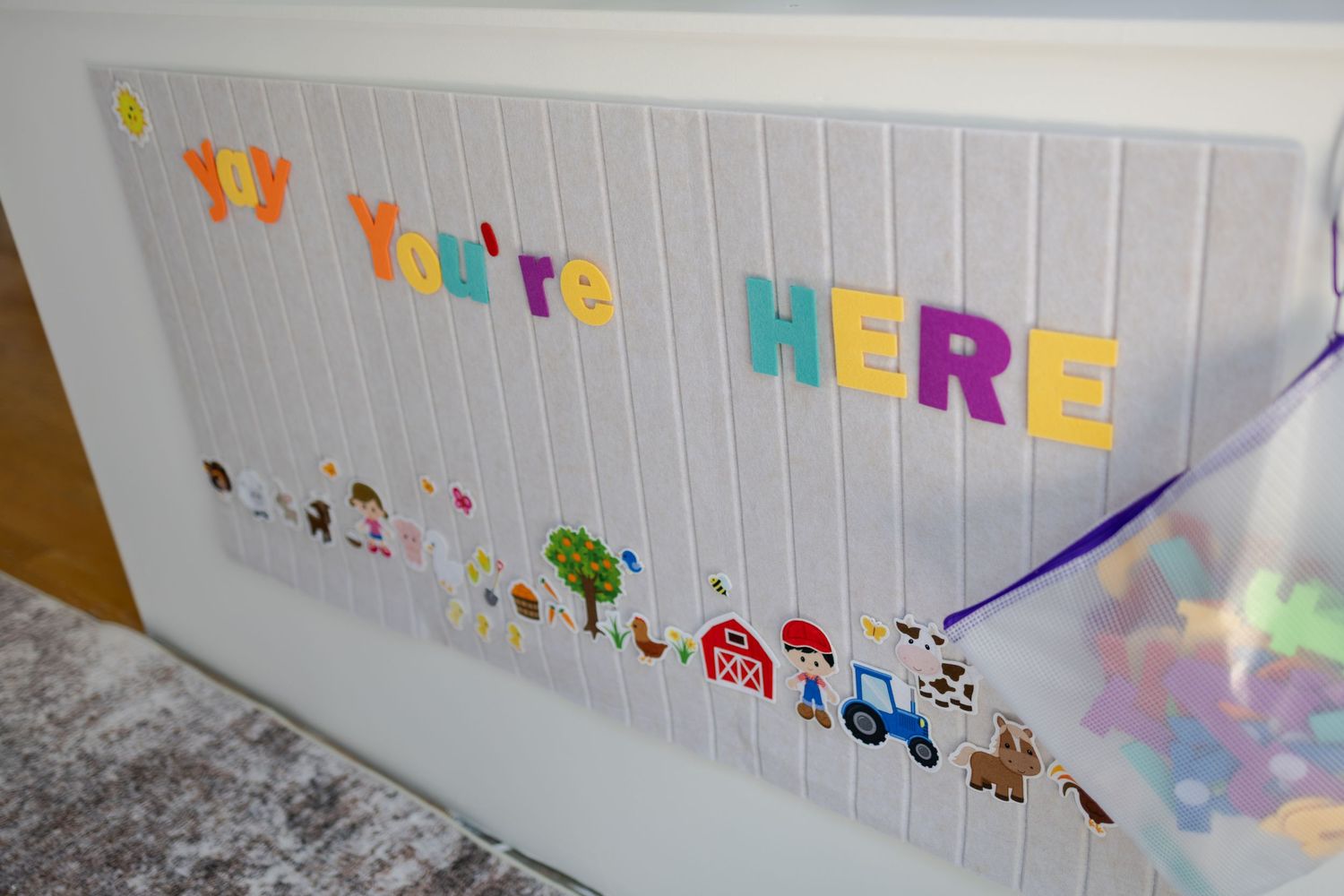 Colorful welcome sign reading You're HERE with farm animal stickers on a white board display.