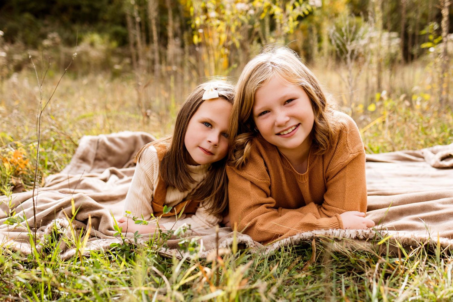 People lying on a blanket in autumn grass during a casual outdoor photo session.