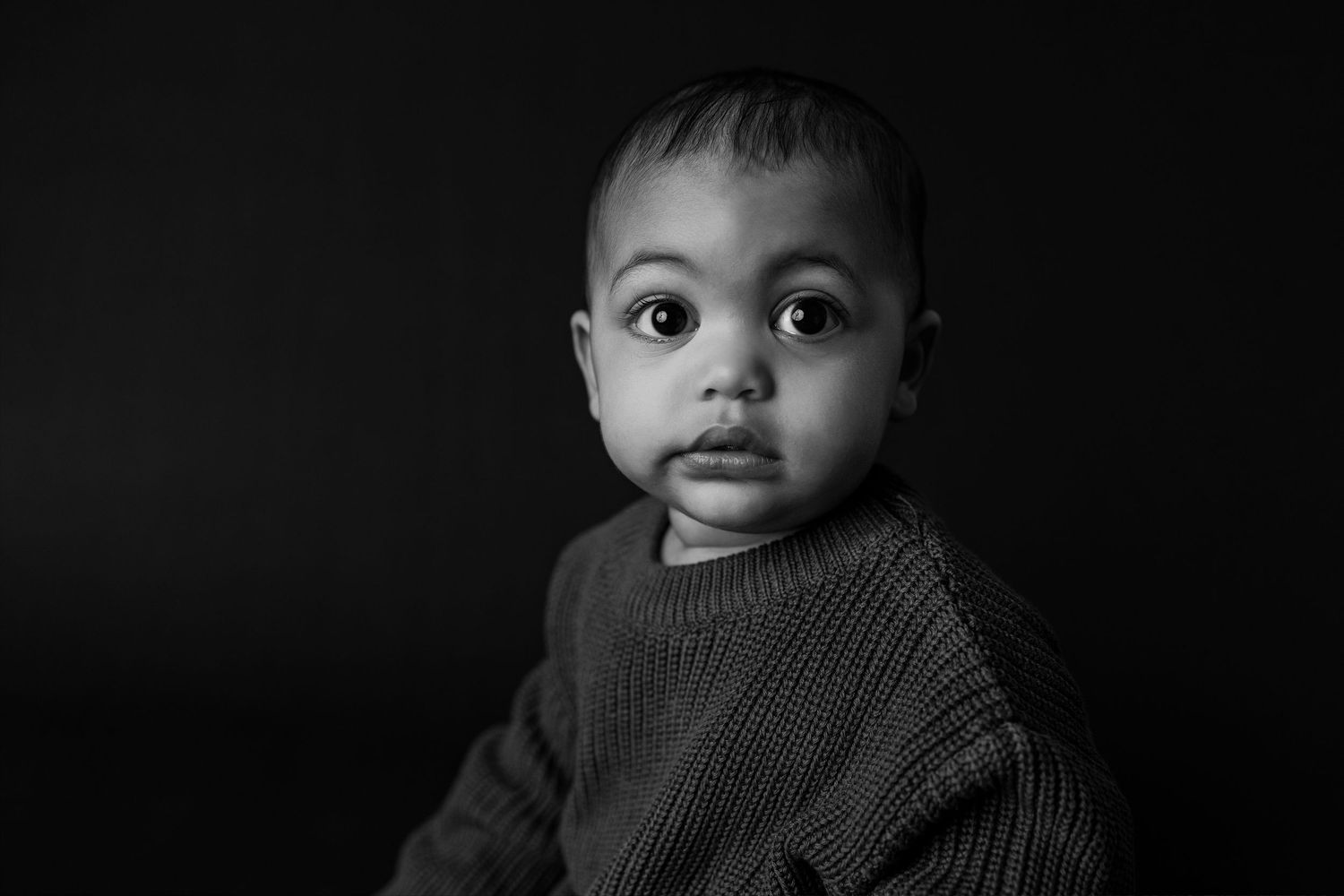 A black and white collage of close-up portraits showing various expressions and angles of a young child.