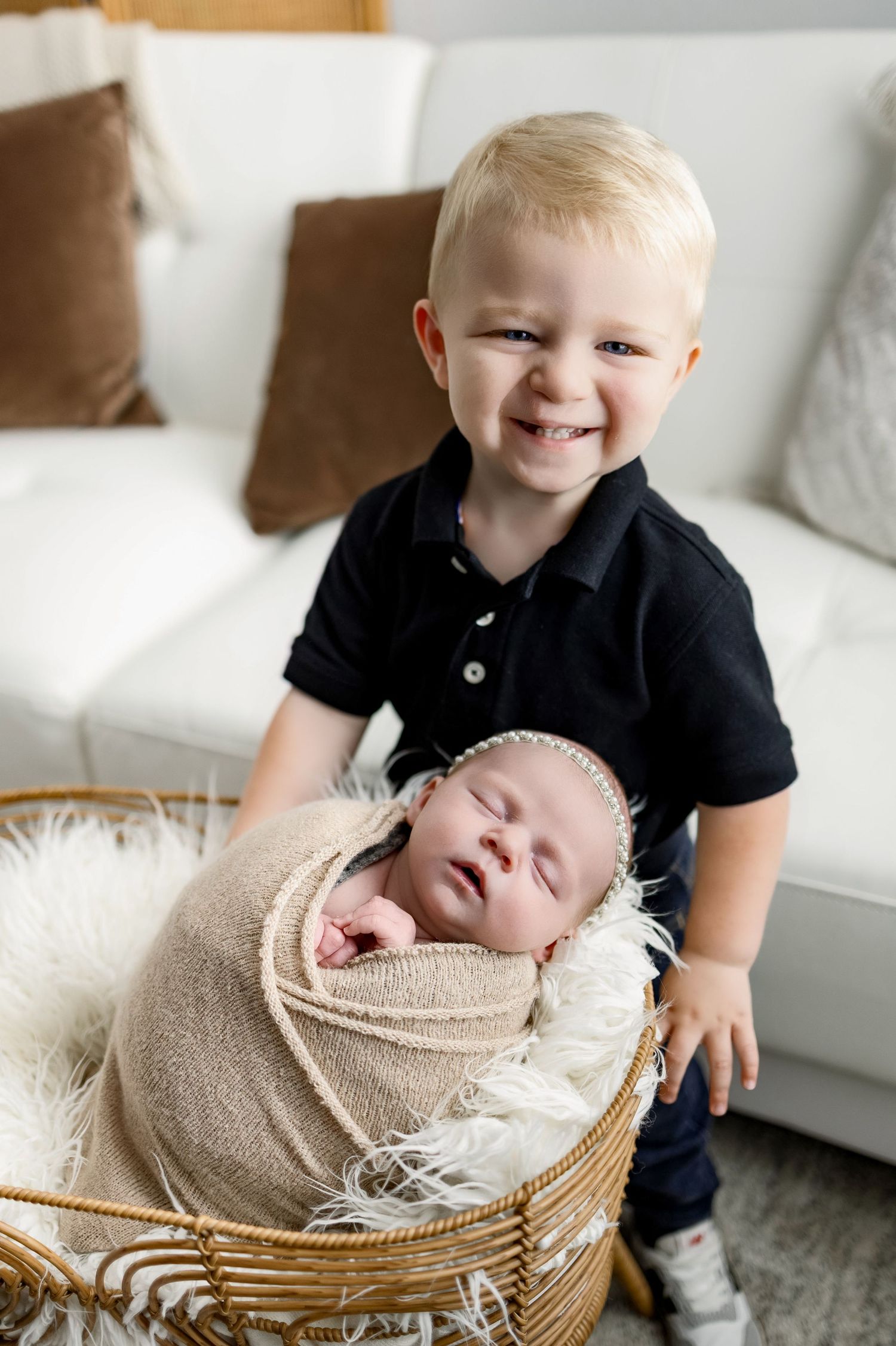 Series of sibling photos showing sweet interaction with newborn baby wrapped in beige blanket in woven basket.