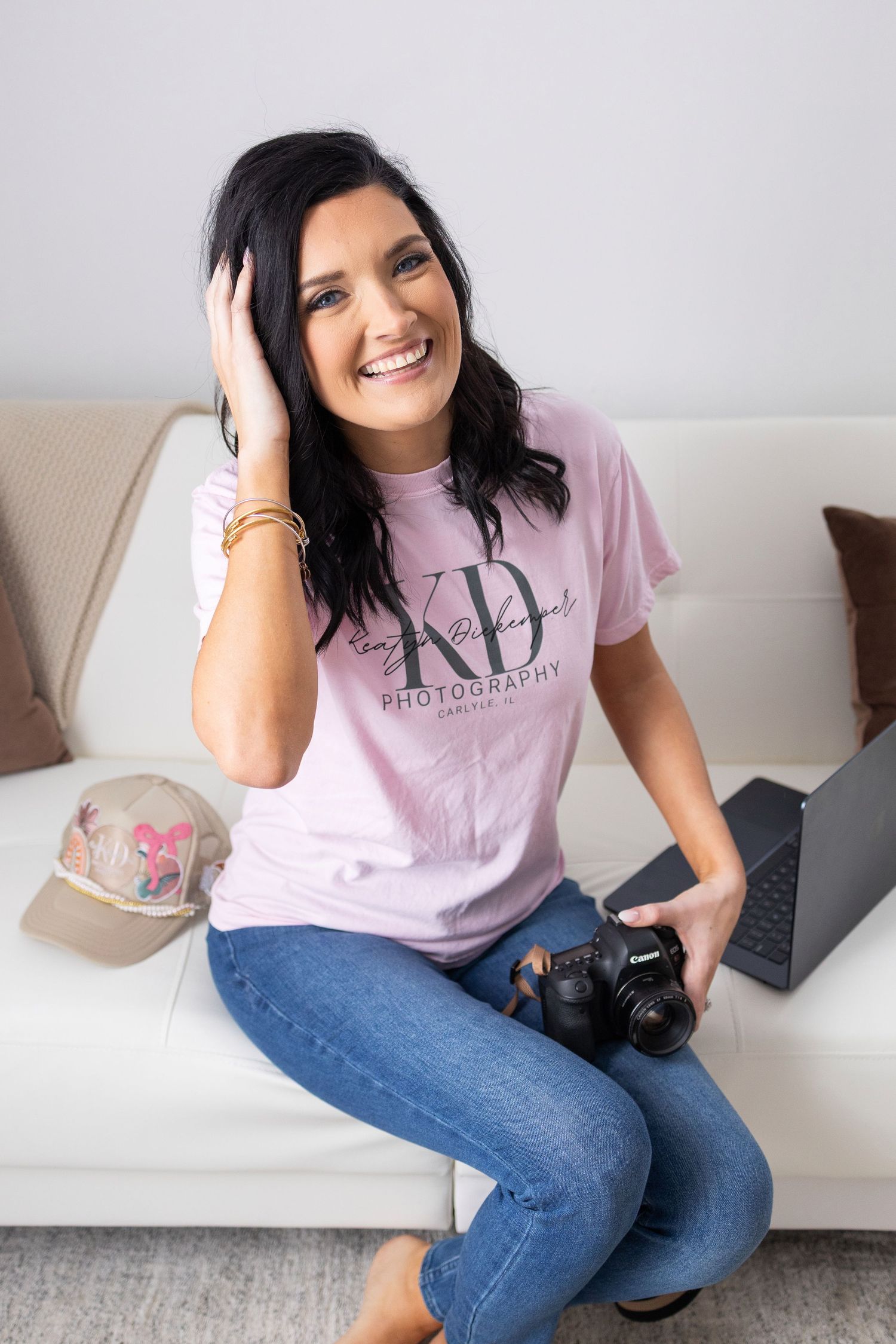 Professional photographer sitting on couch with camera and laptop.