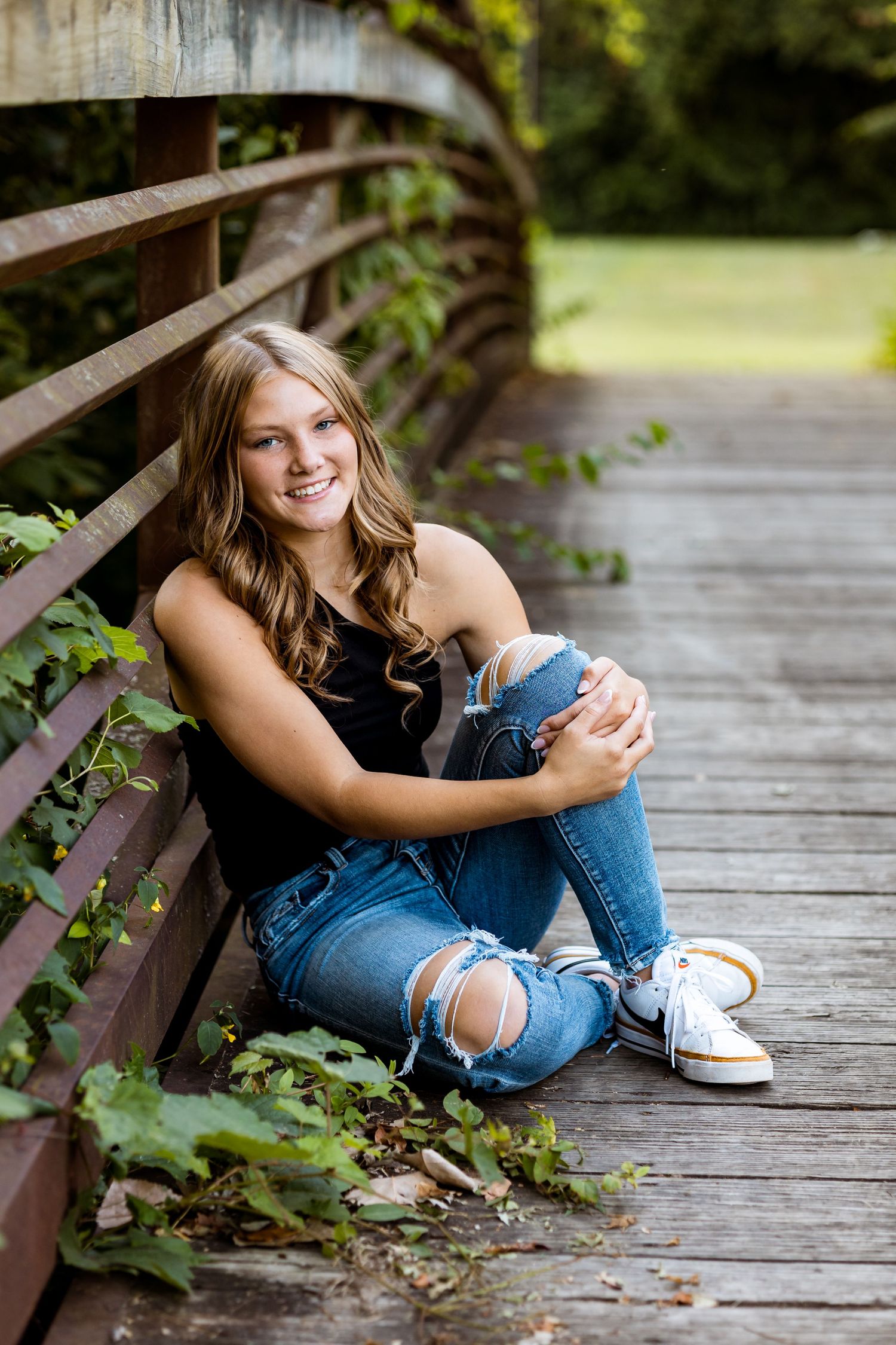 Series of casual portraits on a wooden bridge featuring ripped jeans and relaxed poses in natural lighting.