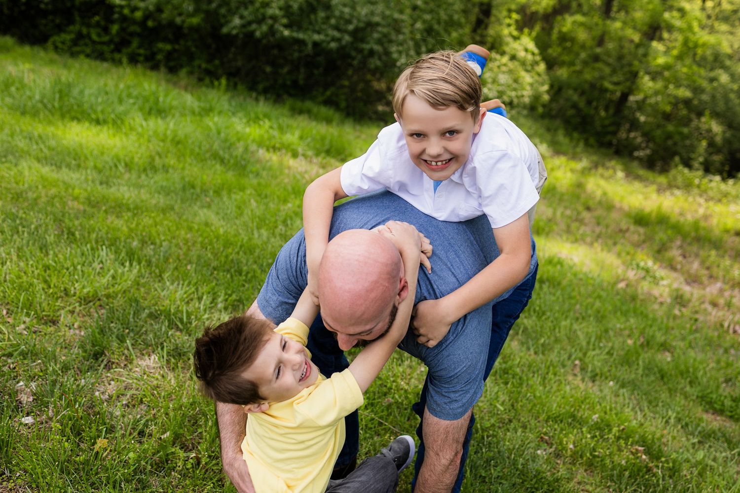 Two people playing with a pink ball on a grassy lawn on a sunny day.