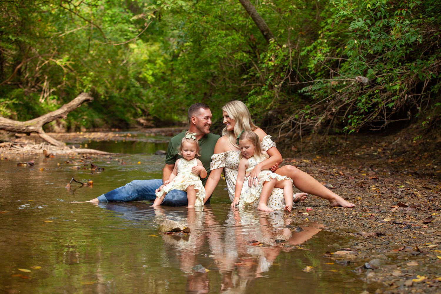 People enjoy splashing and playing in a shallow forest creek on a summer day.
