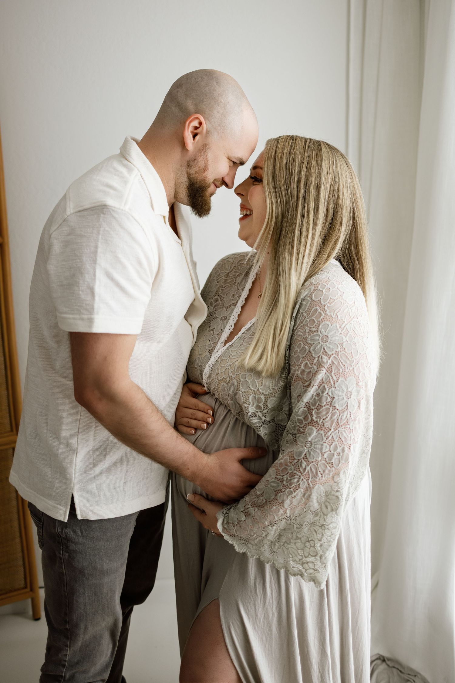 A couple in white clothing shares intimate moments in a sequence of romantic indoor portraits against a light wall.