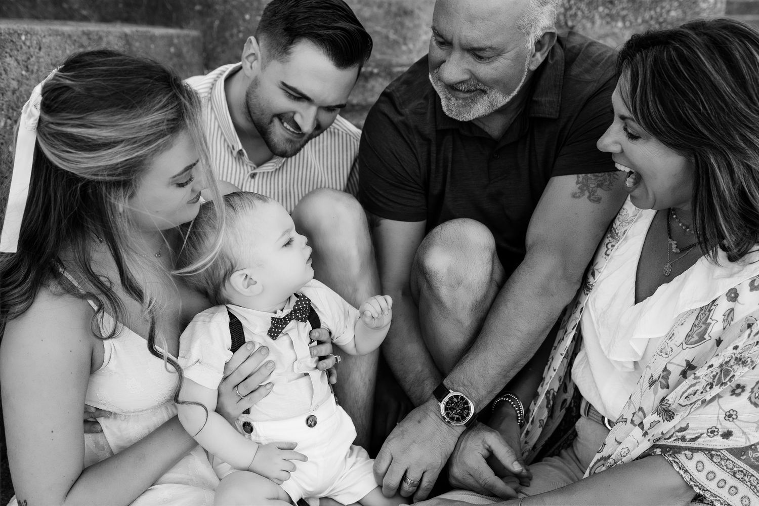 Black-and-white extended-family portrait centered around a smiling baby during an outdoor photography session