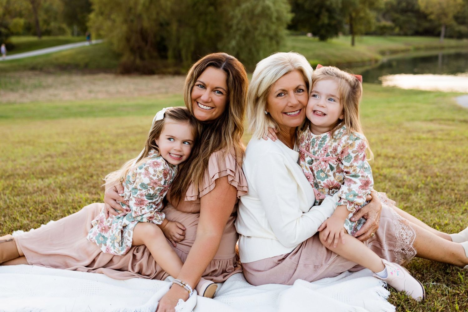 A group poses together on grass wearing coordinated pink and floral outfits for a spring outdoor photoshoot.