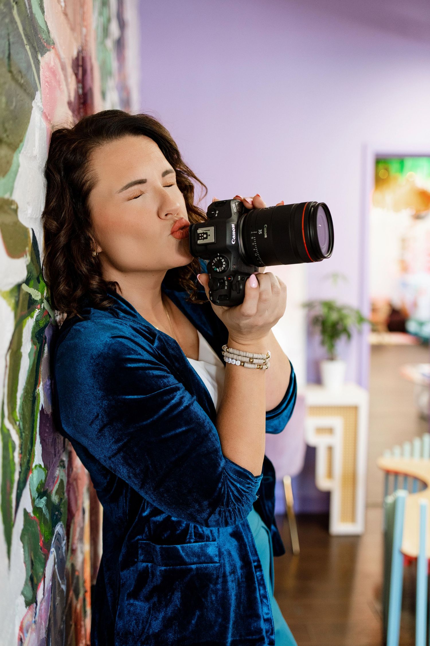 Photographer wearing blue velvet dress shooting with professional camera in indoor setting.