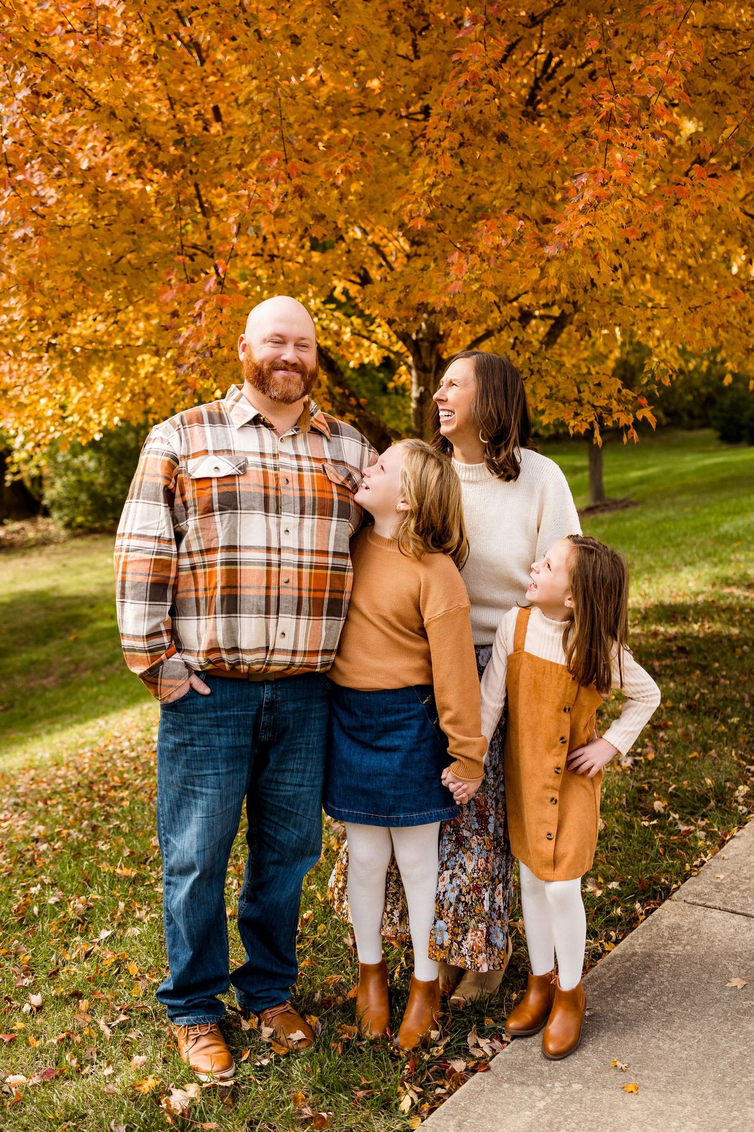 A family shares joyful moments together on a pathway surrounded by vibrant autumn foliage in golden hues.