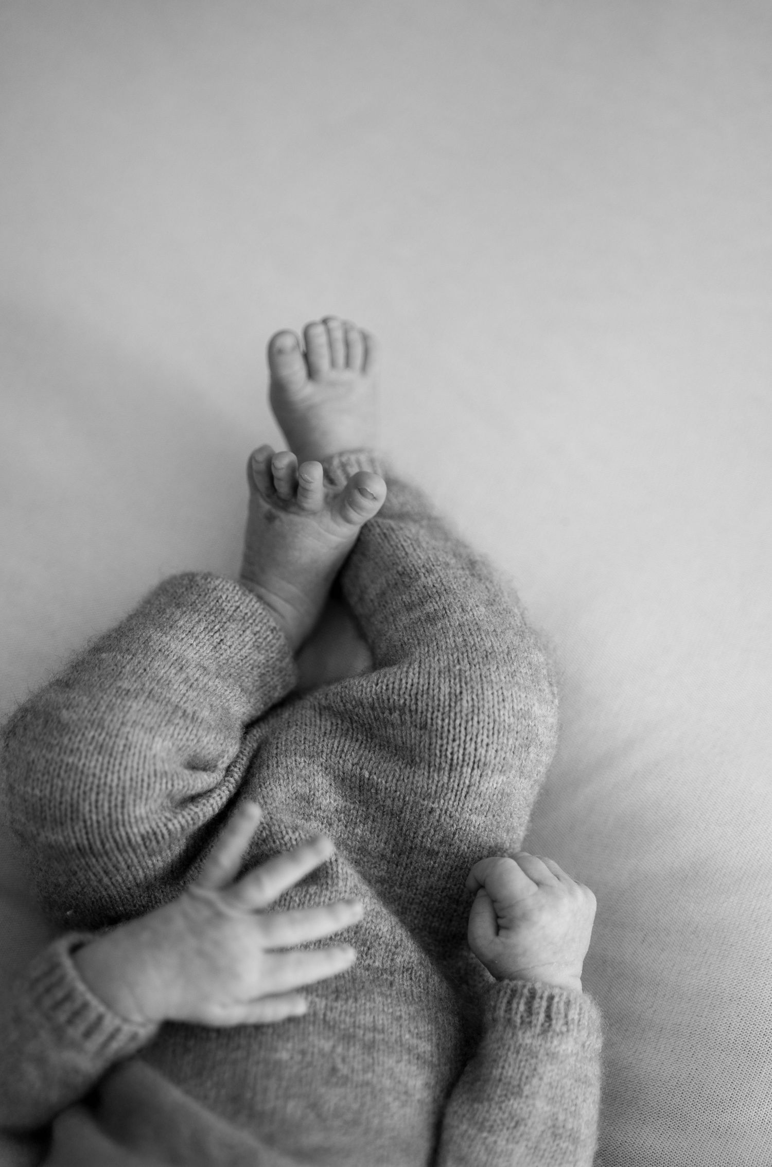 A series of black and white images showing tiny baby feet in soft knitted socks against a light background.