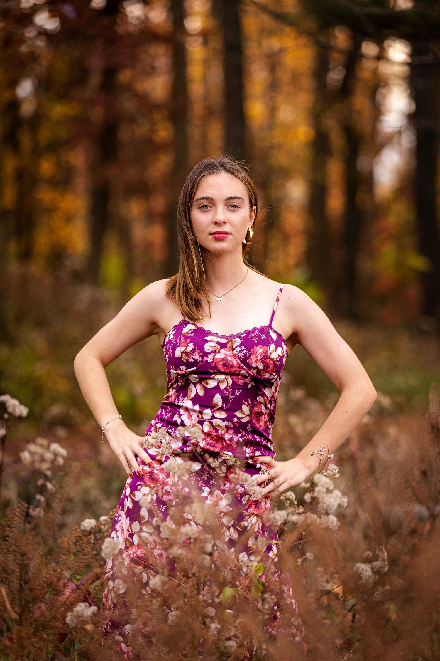 Portrait in purple floral dress amid fall foliage and wildflowers.