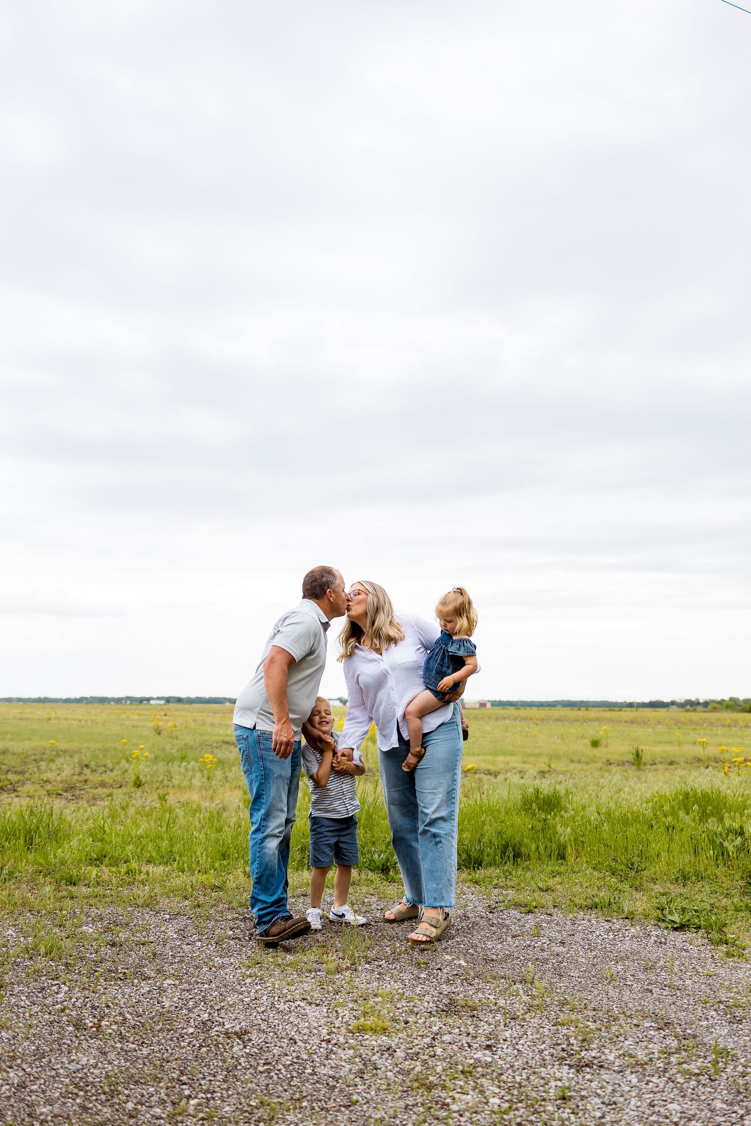 Happy family sharing a tender moment together on a gravel path in a grassy field.