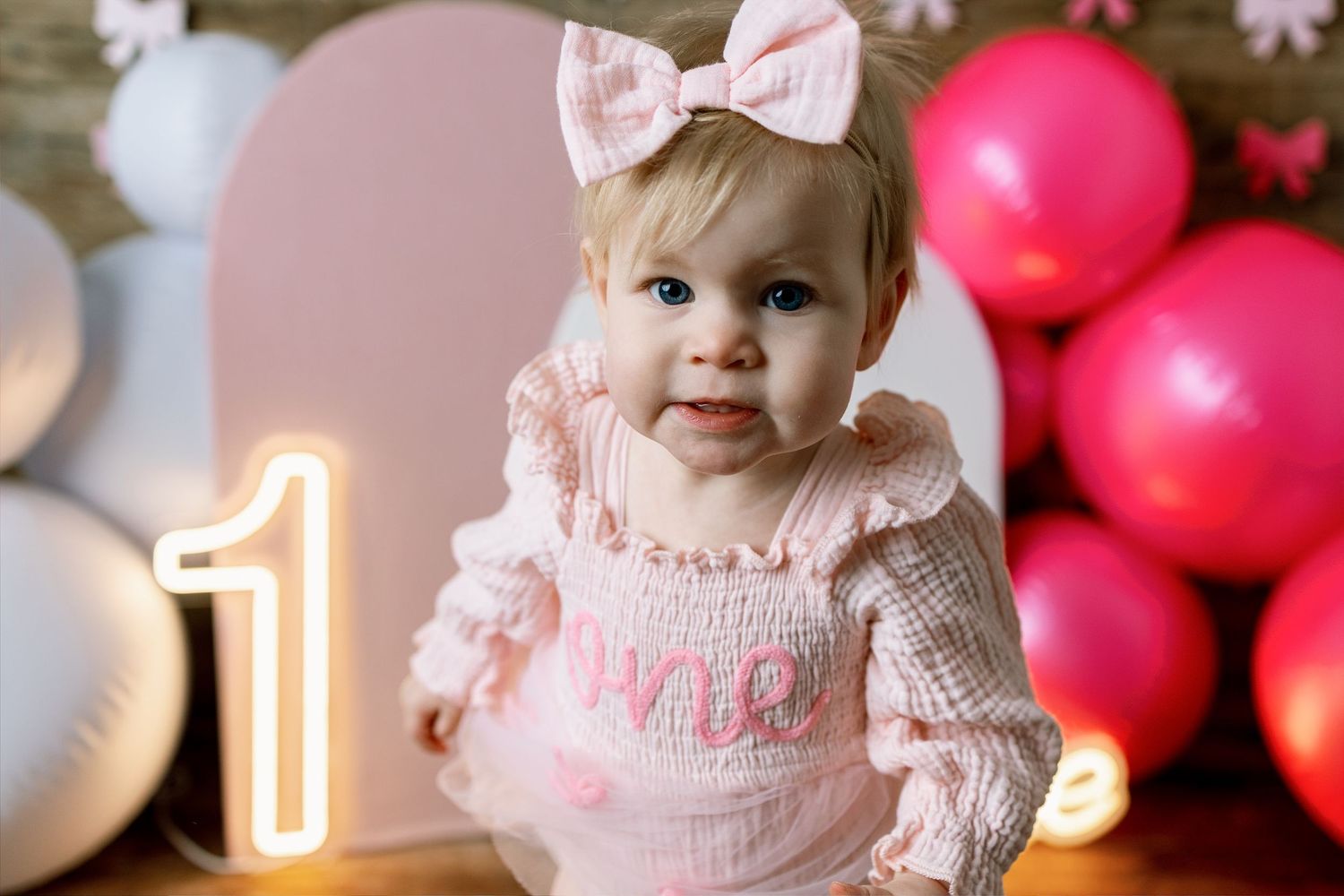 A pink and white birthday celebration setup with balloons and decorative elements for a first birthday party.