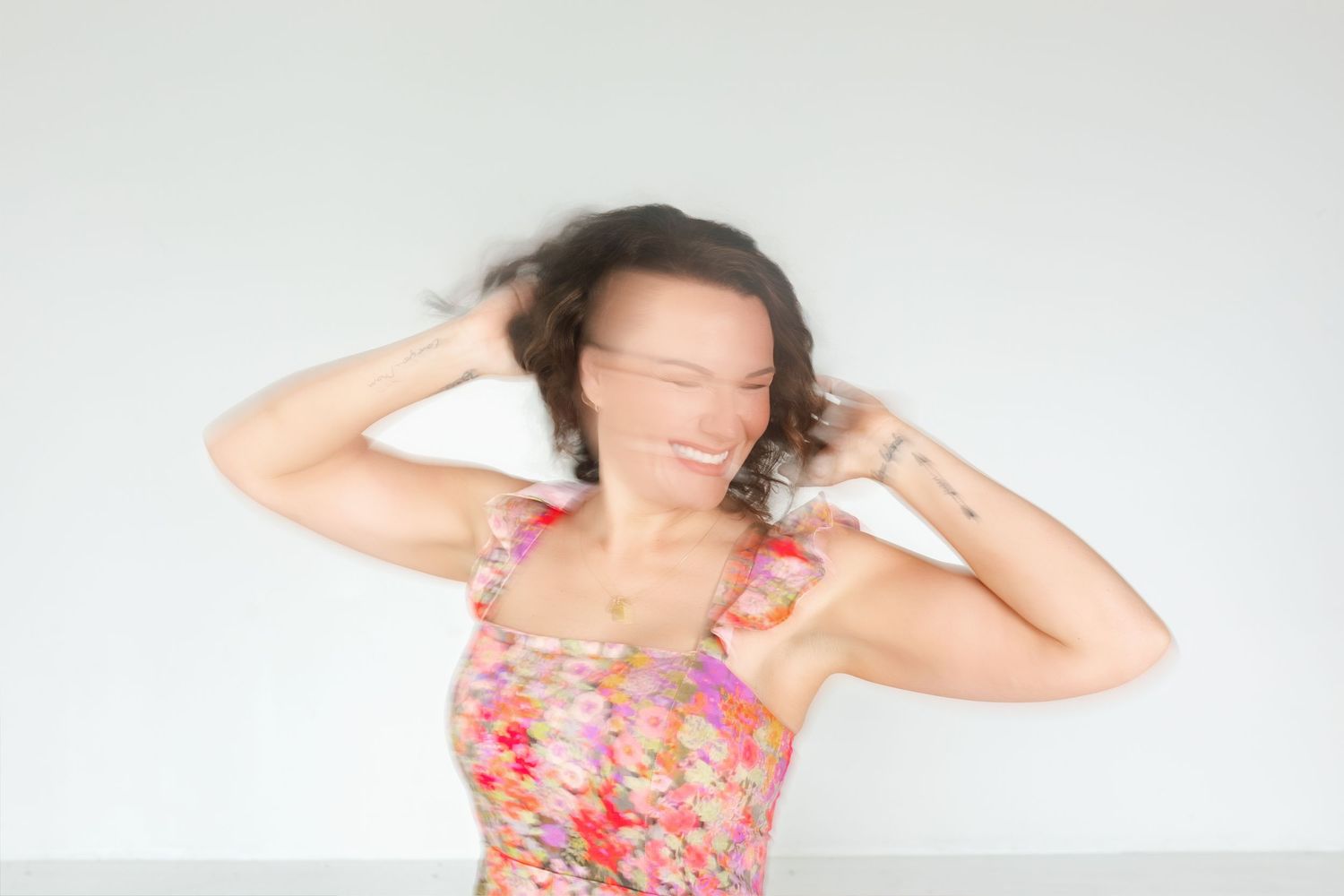 Woman in floral dress poses gracefully against white background in four sequential dance-like movements.