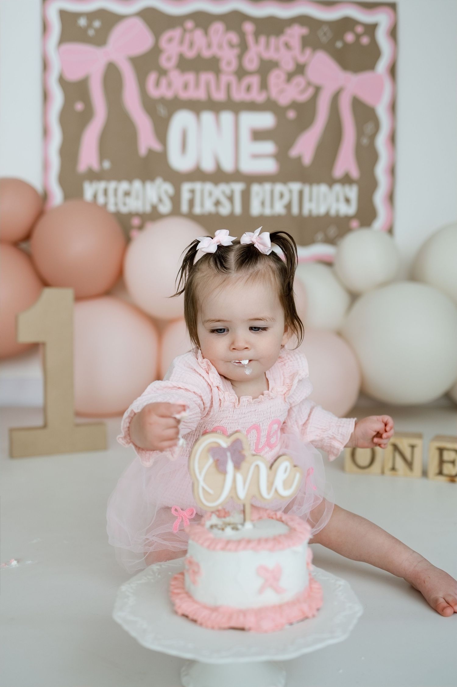 Baby girl in pink tutu dress smashing her first birthday cake at Keegan's ONE birthday party celebration.