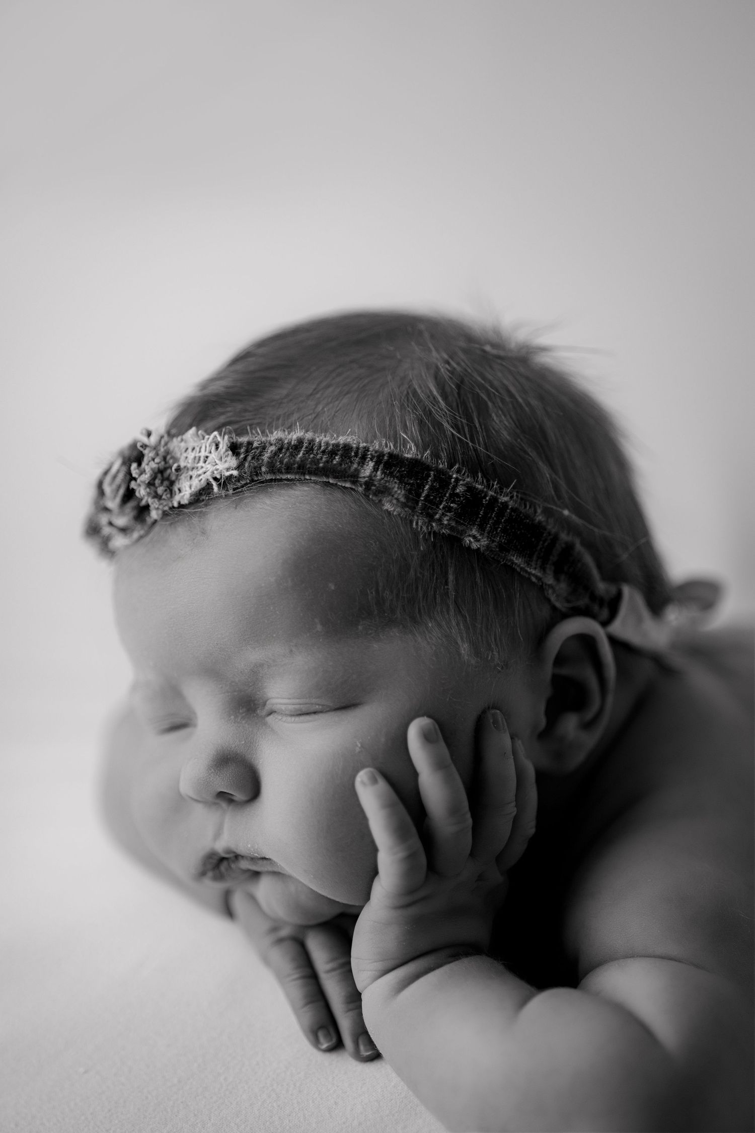 A series of black and white newborn portraits showing peaceful sleeping poses with delicate headbands.