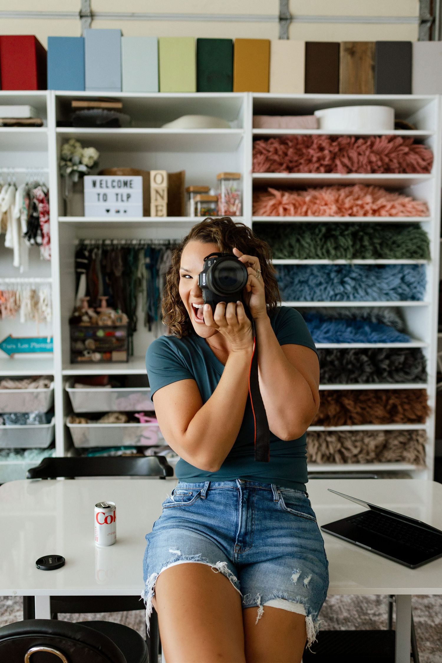 Edwardsville photographer Tara holding her camera in front of the colorful studio prop and backdrop collection