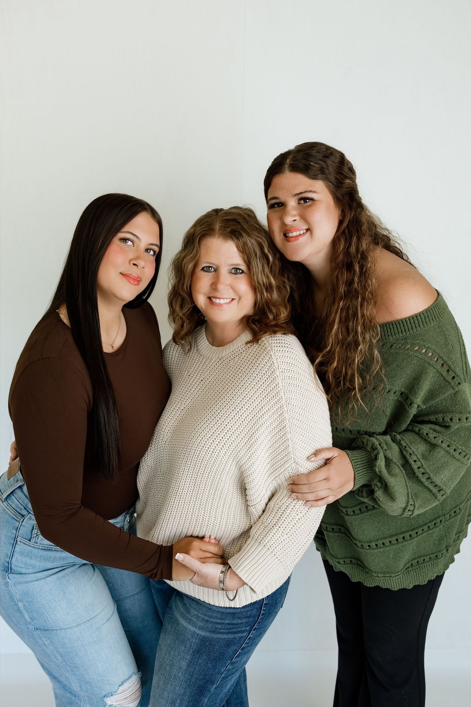 Three women smiling together during a timeless studio portrait session at Tara Lee Photography