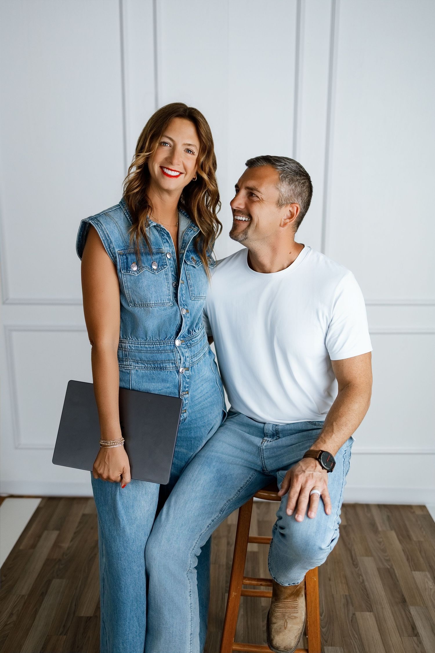 Podcast co-hosts posing with a laptop during a modern studio branding photography session