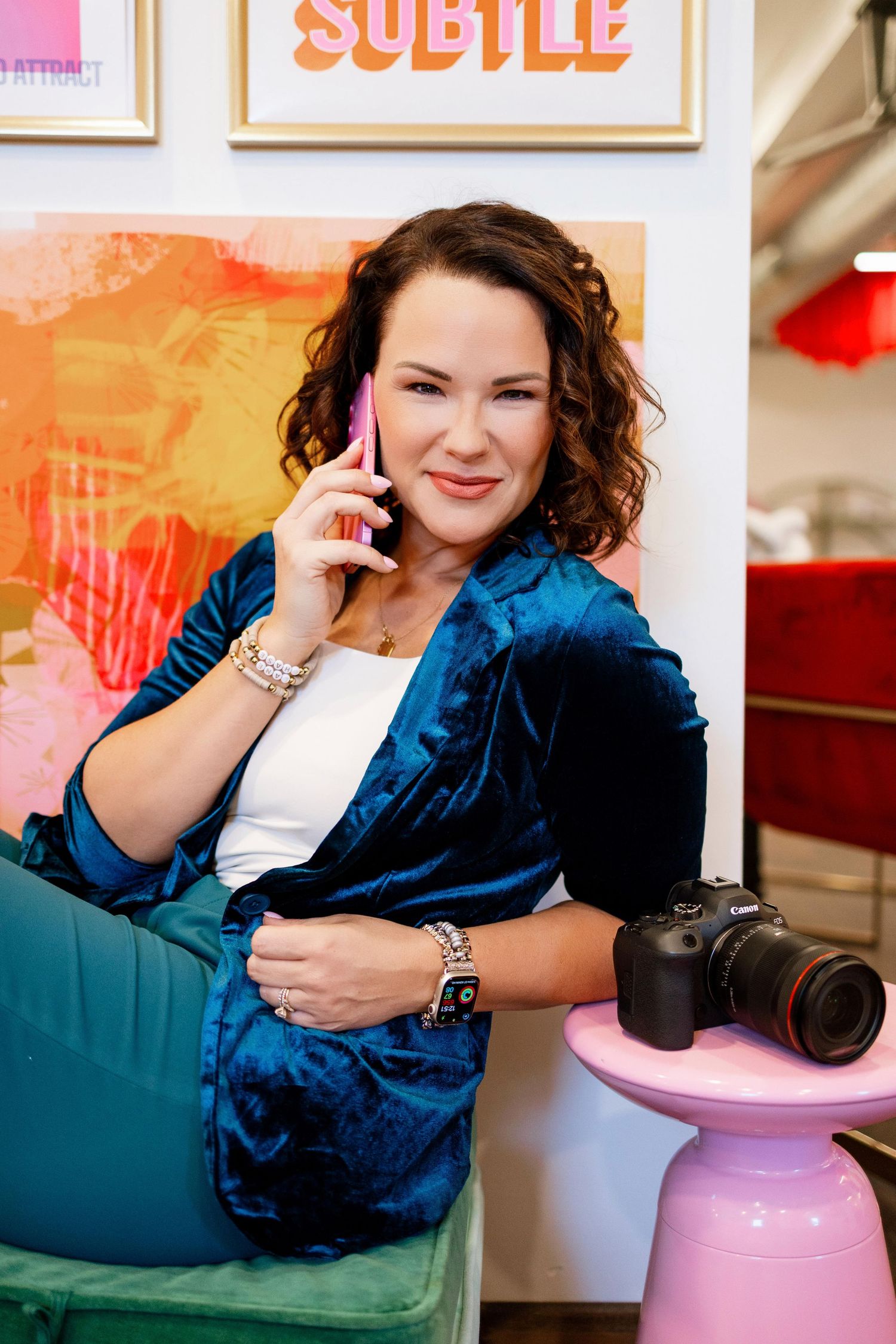 Photographer in blue outfit poses with camera equipment in colorful studio setting.