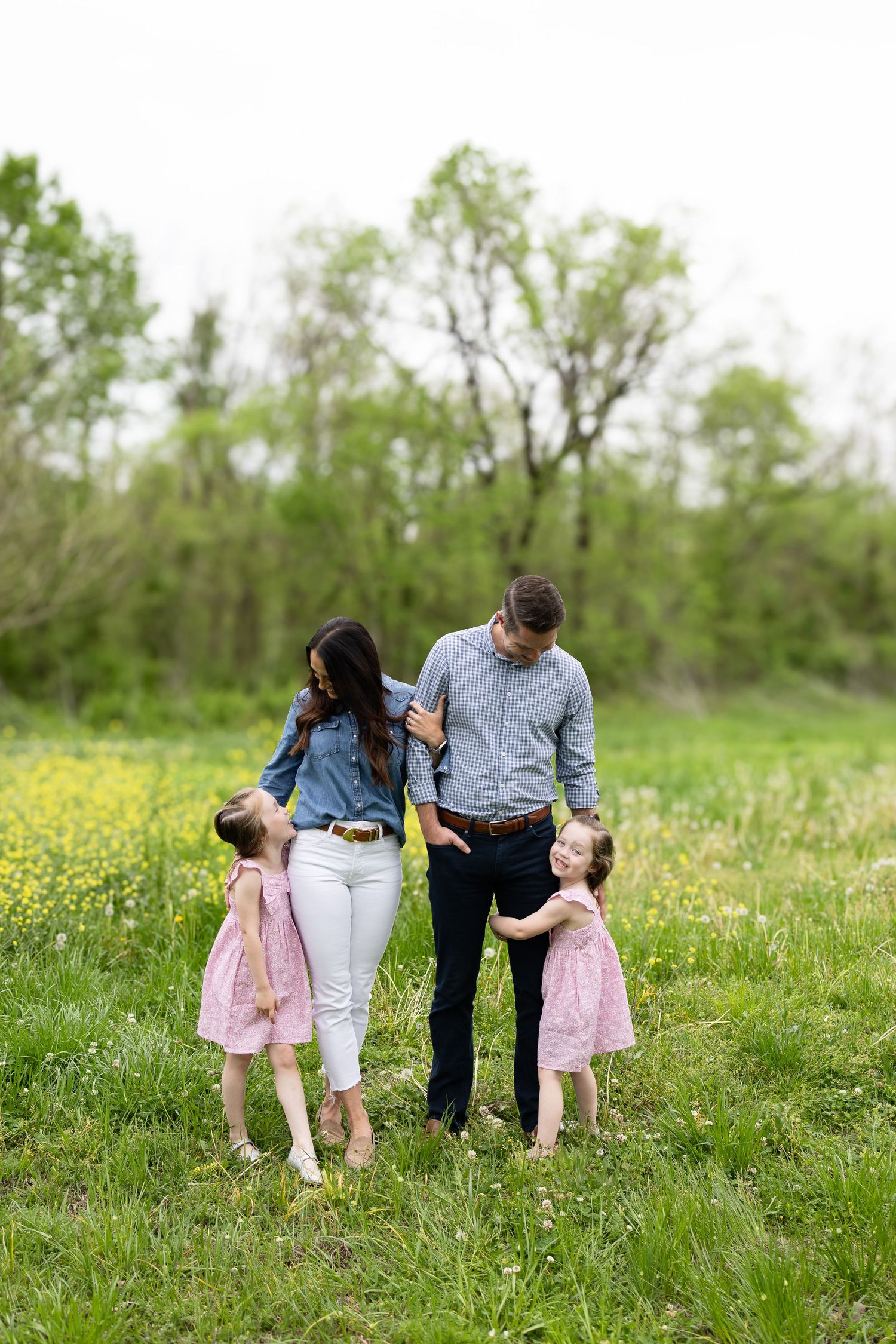 Family walking together through meadow of yellow spring flowers.