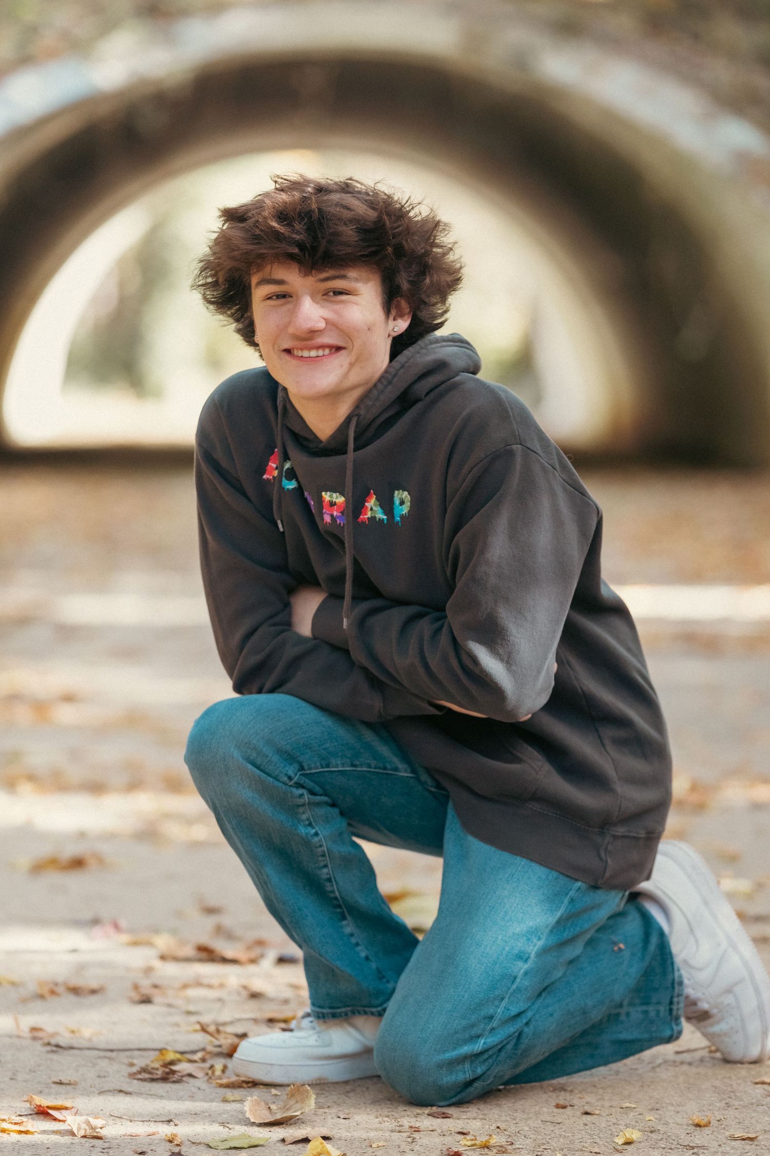 Casual portrait in front of tunnel wearing dark hoodie and jeans.
