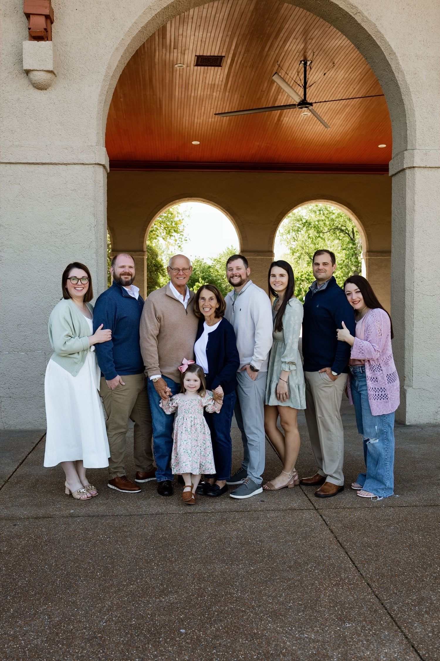 Large extended family posing beneath an arched pavilion during an outdoor multigenerational photography session