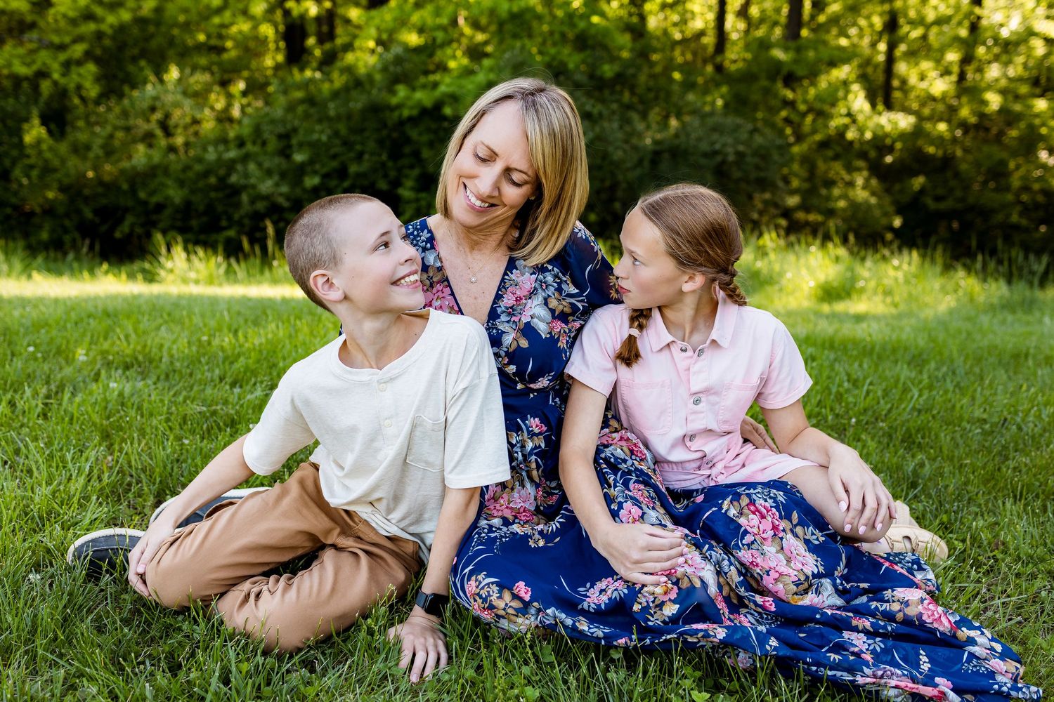 Candid family moment captured on grass with joyful expressions in a park setting.