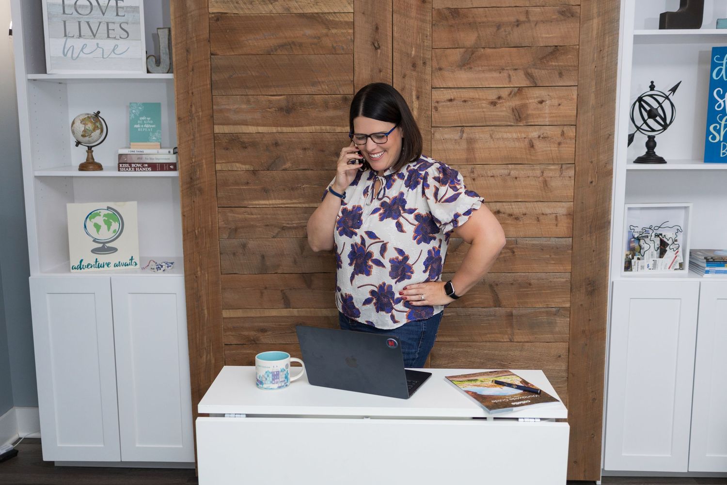 People working at minimalist white desks against a wooden wall backdrop in a modern office setting.