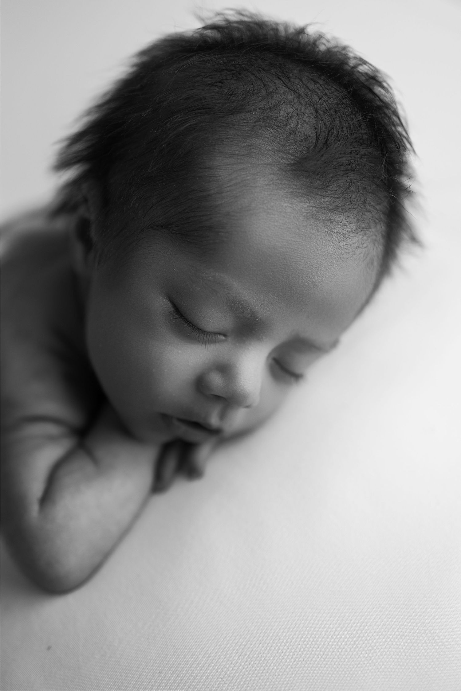 A series of black and white close-up portraits showing a sleeping baby's face from different angles.