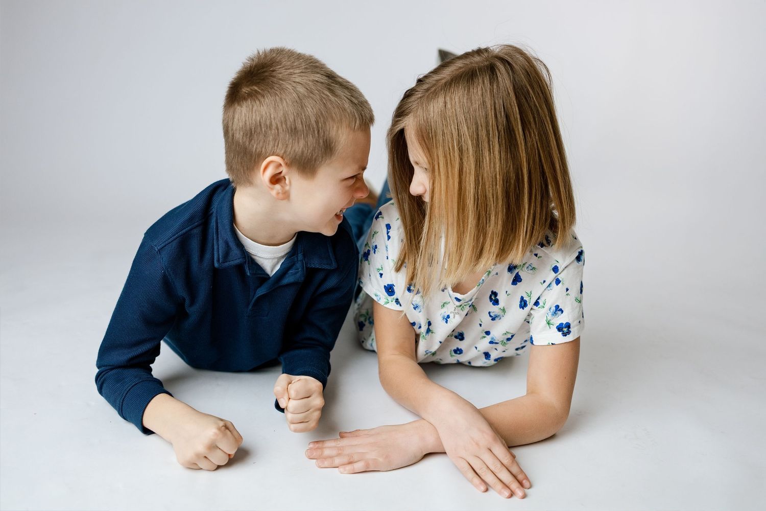 Children lean over a white table while playing and interacting with each other during a candid photo session.