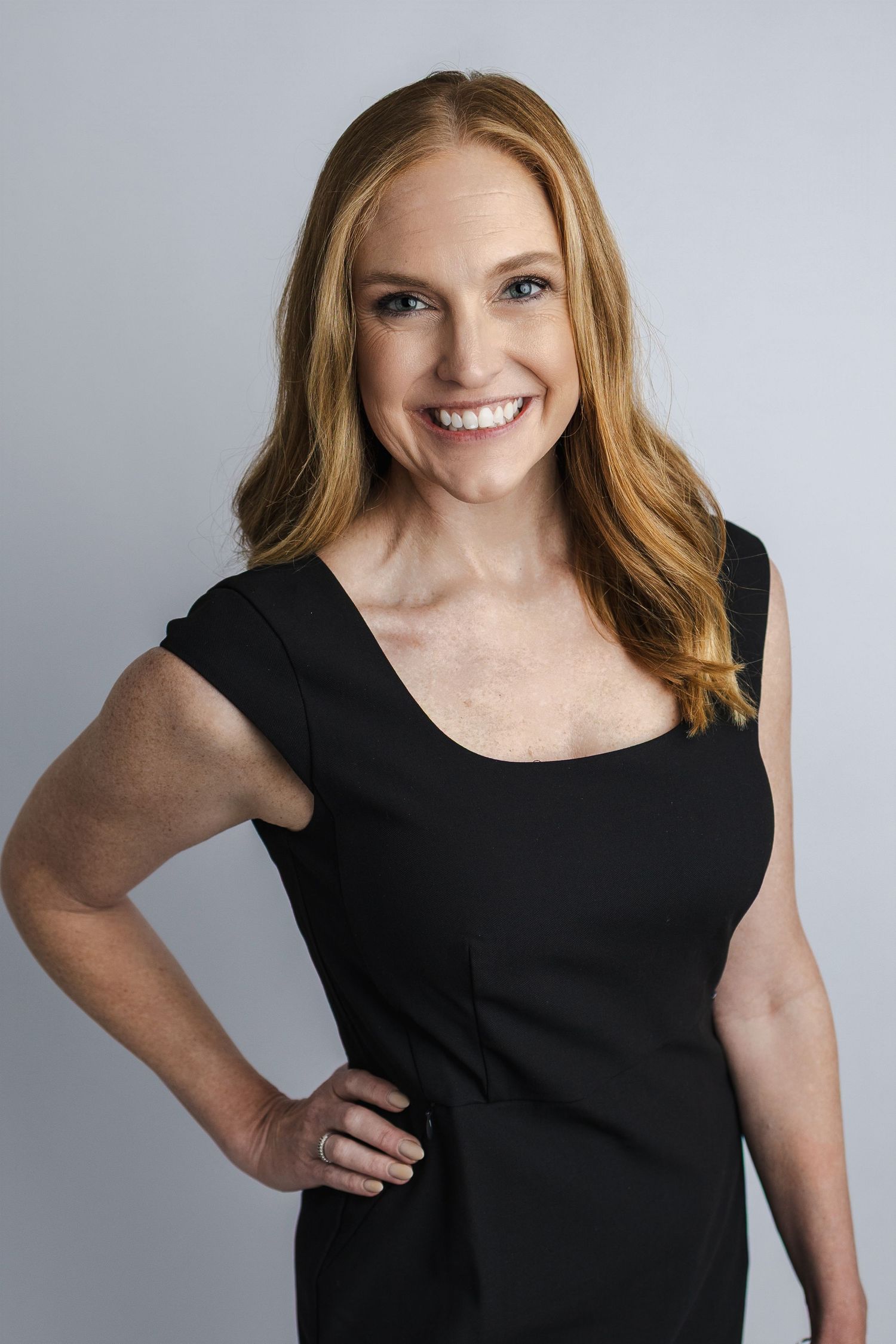 Studio portrait of person wearing black sleeveless dress against grey background.