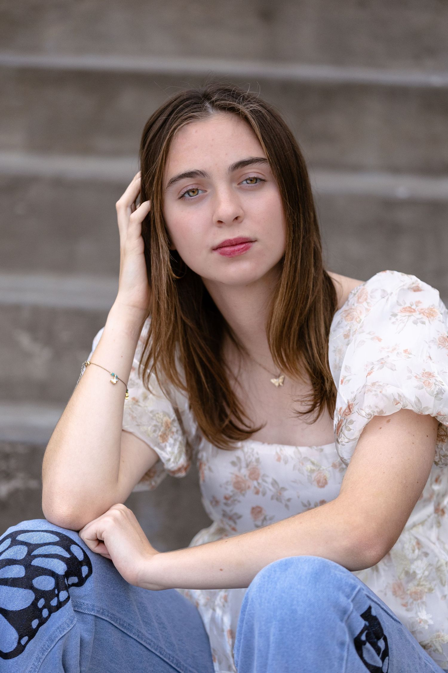 Relaxed pose on steps wearing vintage-style floral top and decorated denim.