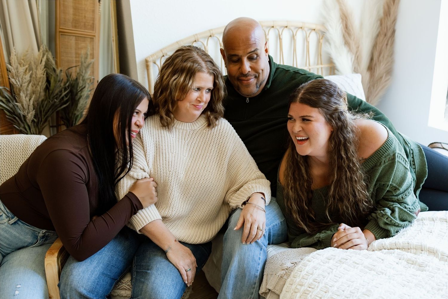Family of four laughing together during a relaxed studio family photography session in Edwardsville