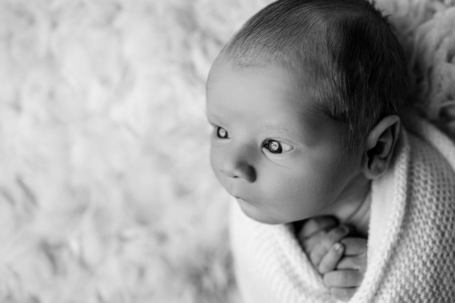 A series of black and white photos showing a baby sleeping peacefully against a textured background.
