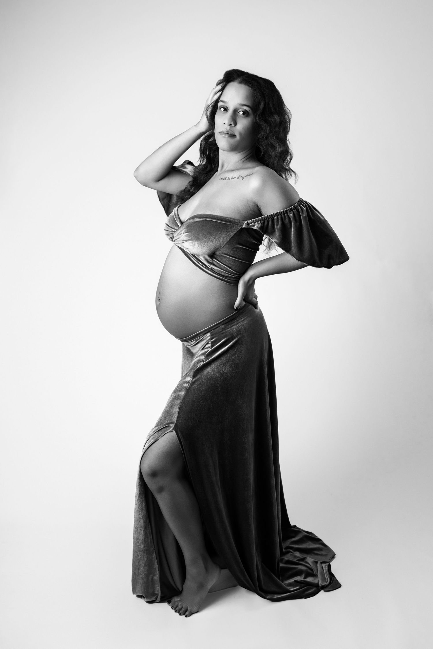Black and white maternity photo series showing artistic poses of a pregnant woman in flowing dress against light background.